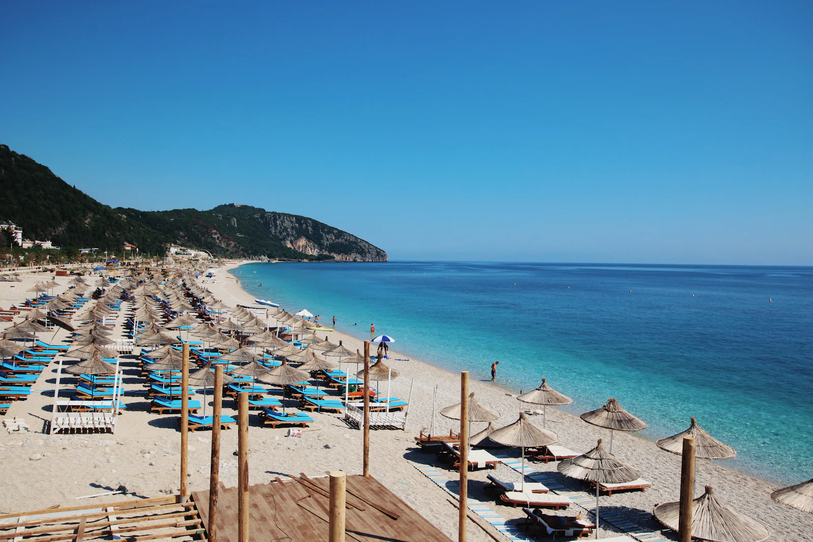 Dhërmi beach with straw umbrellas and clear turquoise water