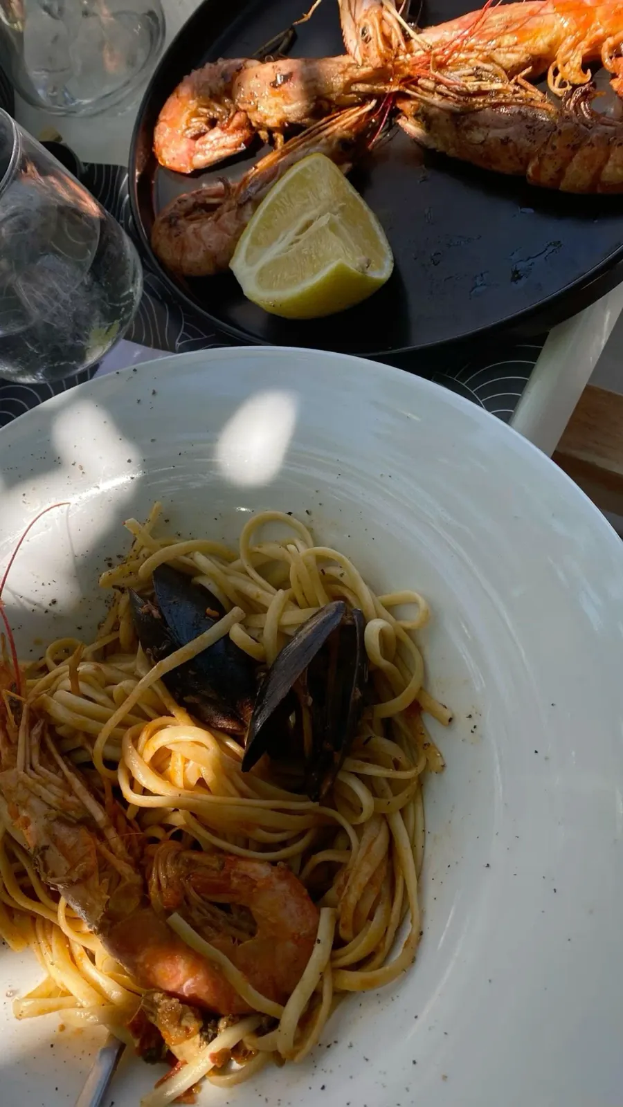 A seafood lunch in Sarandë: grilled prawns with lemon on one plate, linguine with mussels and prawns on the other