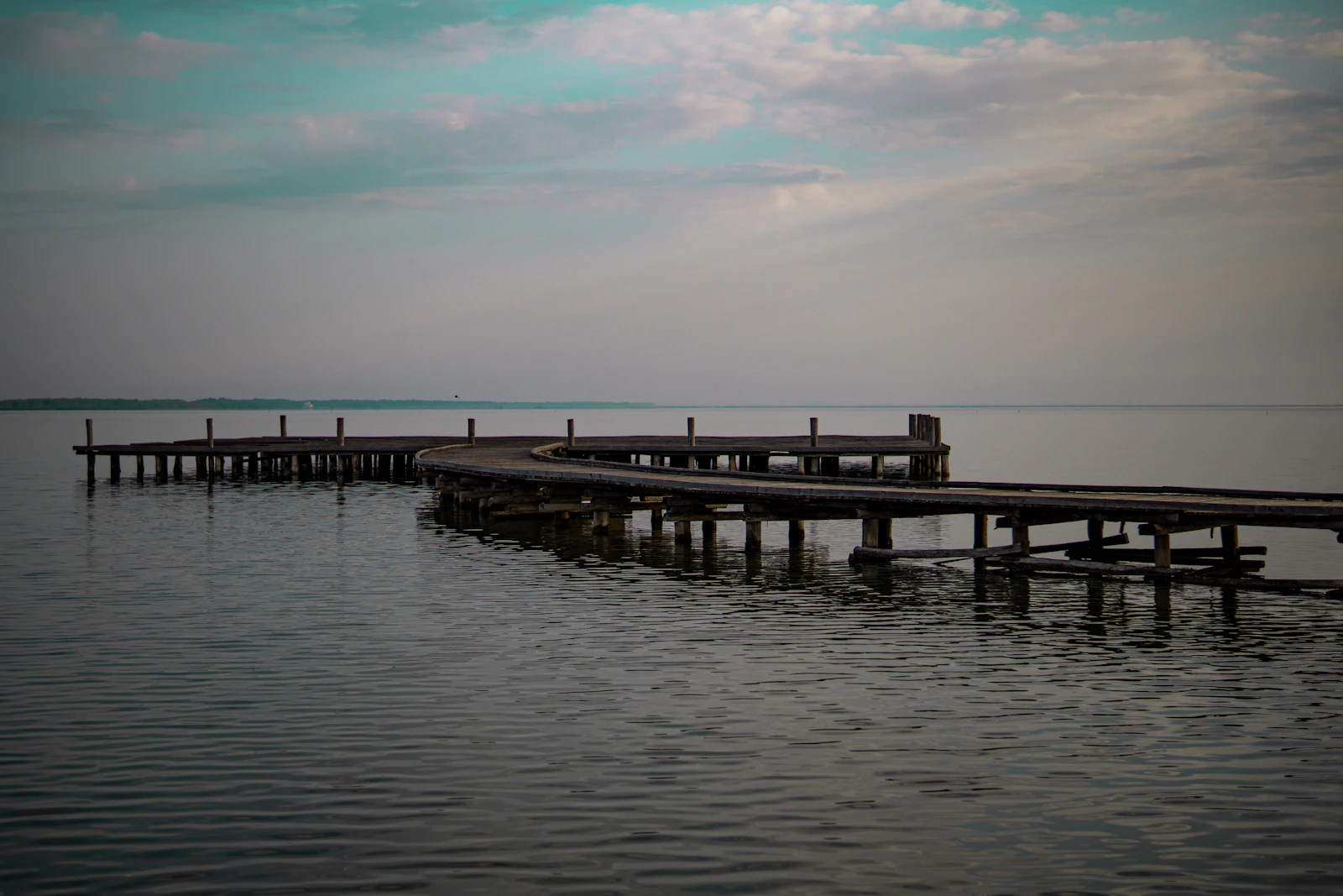 Wooden footbridge curving across the still water of Narta Lagoon at Zvërnec
